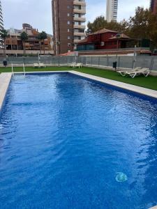 a large blue swimming pool with buildings in the background at Coblanca 41-spectacular views-gym-heated pool-sauna-jacuzzi-wifi-3 minutes walk from the sear in Benidorm