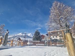 a snow covered yard with a fence and mountains at Das Steinmetzhäuschen in Virgen