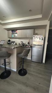 a kitchen with two bar stools and a refrigerator at Modern apartment in Angelopolis - 2 bedrooms in Tlazcalancingo