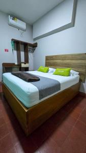 a large bed with two green pillows on it at Hotel Skal Inn in Barranquilla