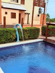a pool with a water fountain in front of a house at Flat Studio Casal - Praia da Lagoa do P a u - Coruripe in Coruripe +3 photos