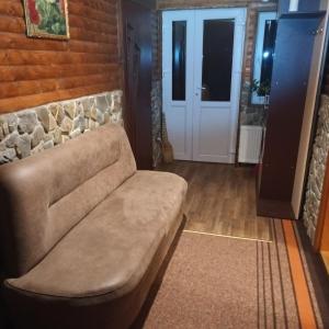 a couch in a living room with a stone wall at У Матвія in Vorokhta