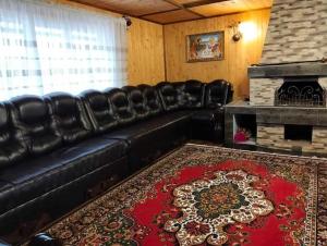 a black leather couch in a living room with a fireplace at У Матвія in Vorokhta