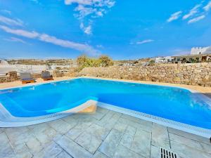 a swimming pool with a stone wall and blue water at Grace Villa Mykonos in Mikonos