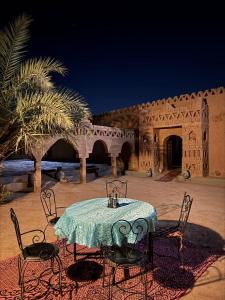 a table and chairs in front of a building at Auberge el oasis mharech in Foum Mharech