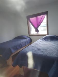 a bedroom with two beds and a window with a purple curtain at Cabañas Drü 3 in Coihaique