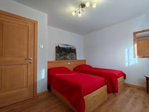 a bedroom with two beds with red sheets at Appartamento panoramico 1 in Dosoledo