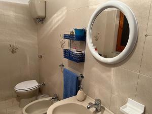 a bathroom with a toilet and a sink and a mirror at Casa Primula - Family Country House immersa nel verde a 5 min dal Mare in Ricadi