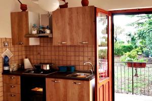 a kitchen with wooden cabinets and a sink and a window at Casa Primula - Family Country House immersa nel verde a 5 min dal Mare in Ricadi +28 photos