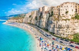 a beach with umbrellas and crowds of people on it at Casa Primula - Family Country House immersa nel verde a 5 min dal Mare in Ricadi