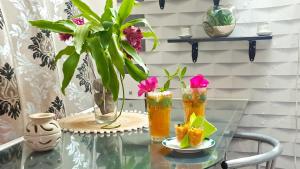 a glass table with two vases and flowers on it at Le LiloVert - Studio 24 m2 in Le Carbet