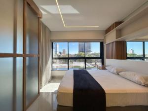 a bedroom with a large bed and large windows at Studio Central, Tranquilo e Confortavel in Campo Grande +14 photos