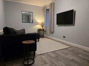 a living room with a couch and a television on a wall at Wick Harbour View Apartment - 2 Beds - Sleeps 3 - Ideal for Couples in Wick