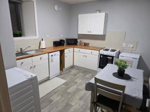 a kitchen with white cabinets and a table and a sink at Wick Harbour View Apartment - 2 Beds - Sleeps 3 - Ideal for Couples in Wick