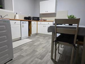a kitchen with white cabinets and a table and a chair at Wick Harbour View Apartment - 2 Beds - Sleeps 3 - Ideal for Couples in Wick +4 photos
