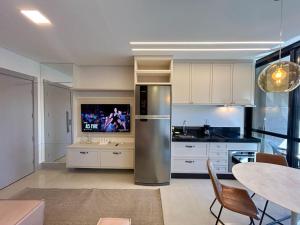 a kitchen with a stainless steel refrigerator and a table at Studio Central, Tranquilo e Confortavel in Campo Grande