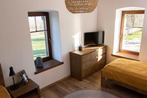 a bedroom with a bed and a tv and two windows at Pirk Vendégház Vászoly in Vászoly