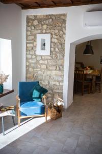 a living room with a blue chair and a stone wall at Pirk Vendégház Vászoly in Vászoly +43 photos