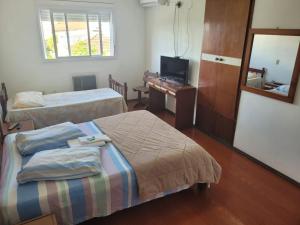 a hotel room with two beds and a television at Novo Hotel in Caçapava do Sul
