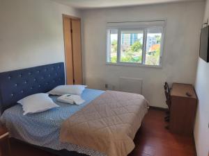 a bedroom with a bed with two pillows and a window at Novo Hotel in Caçapava do Sul