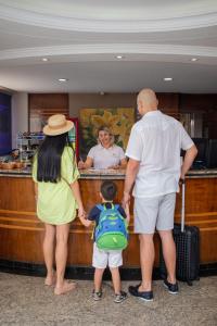 a man and a woman and a child standing at a counter at Hot Star Thermas Hotel in Caldas Novas