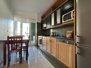 a kitchen with wooden cabinets and a table with a sink at Forum Madeira dla par in Funchal