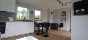 a kitchen with white cabinets and black stools at Domek w okolicy Karpacza in Marczyce