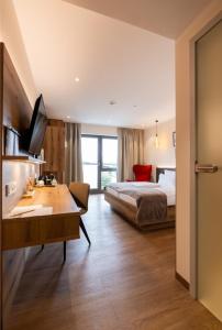 ein Schlafzimmer mit einem Bett und einem Schreibtisch in einem Zimmer in der Unterkunft Weinzuhause Hotel-Restaurant-Vinothek in Mommenheim