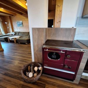 a kitchen with a red stove and a basket of logs at Ferienhaus Hochfelner in Sankt Marein bei Knittelfeld +32 photos