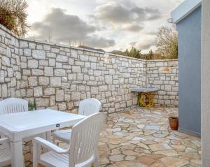 a patio with a white table and chairs and a stone wall at Villa Voka in Acharavi