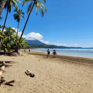 a group of people walking on a beach with palm trees at Casa Uvita Bay in Uvita