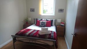 Un dormitorio con una cama con almohadas rosas y una ventana en eApartments, en Edimburgo