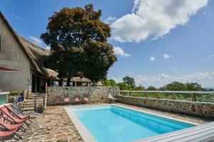 a swimming pool with chairs and a stone wall at les bois de saint auvent in La Geneytouse