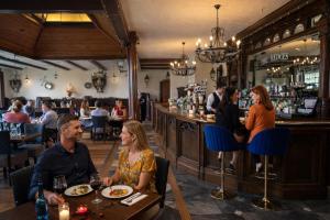 a group of people sitting at a bar in a restaurant at The Dark Hedges Hotel in Stranocum