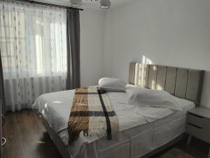 a bedroom with a large bed with white sheets and a window at Apartament Alice & Denis in Tohanu Nou