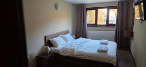 a bedroom with a bed with white sheets and a window at Къща за гости Гергана in Ribarica