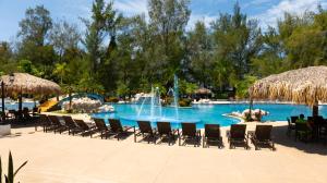 a pool at a resort with chairs and a fountain at La Ensenada Beach Resort in Tela