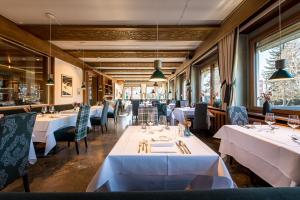 ein Restaurant mit weißen Tischen und Stühlen und Fenstern in der Unterkunft Hotel ANDER in Bruneck