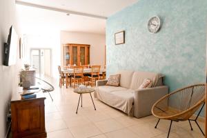 a living room with a couch and a clock on the wall at Il-Qastna Holiday House in Żejtun