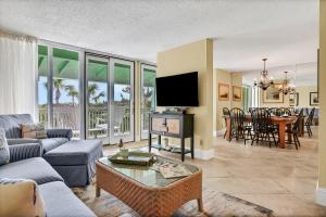 a living room with a couch and a table with a tv at Oceanfront condo with direct beach access, pool, balcony, grilling area, & AC in Fernandina Beach