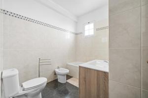 a white bathroom with a toilet and a sink at Caniço Seaview House in Caniço +37 photos