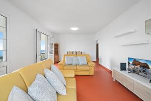 a living room with a yellow couch and a tv at Caniço Seaview House in Caniço