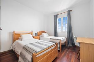 a bedroom with two beds and a window at Caniço Seaview House in Caniço