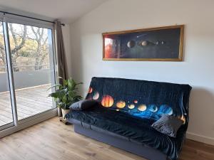 a black couch in a living room with a sliding glass door at L'abeille sous les étoiles in Saint-Michel-lʼObservatoire