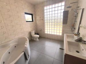 a bathroom with a tub and a toilet and a sink at Résidence Ermitage in Ouidah +19 photos