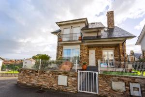 a brick house with a fence on the front at Los cuetos, casa para 6 personas con jardín y parking, a pocos minutos de Suances in Suances