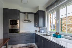 a kitchen with blue cabinets and a sink and a window at Los cuetos, casa para 6 personas con jardín y parking, a pocos minutos de Suances in Suances