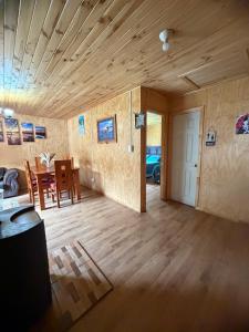 a living room with a wooden ceiling and a dining room at Cabaña A & M in Chaitén