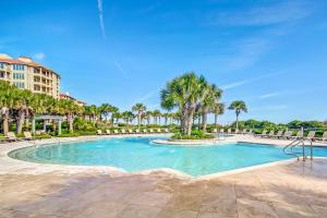 a swimming pool with palm trees and a building at Oceanfront condo with panoramic views, shared pool, and private washer & dryer in Fernandina Beach