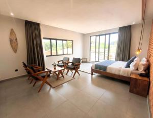 a bedroom with a bed and a table and chairs at Résidence Ermitage in Ouidah